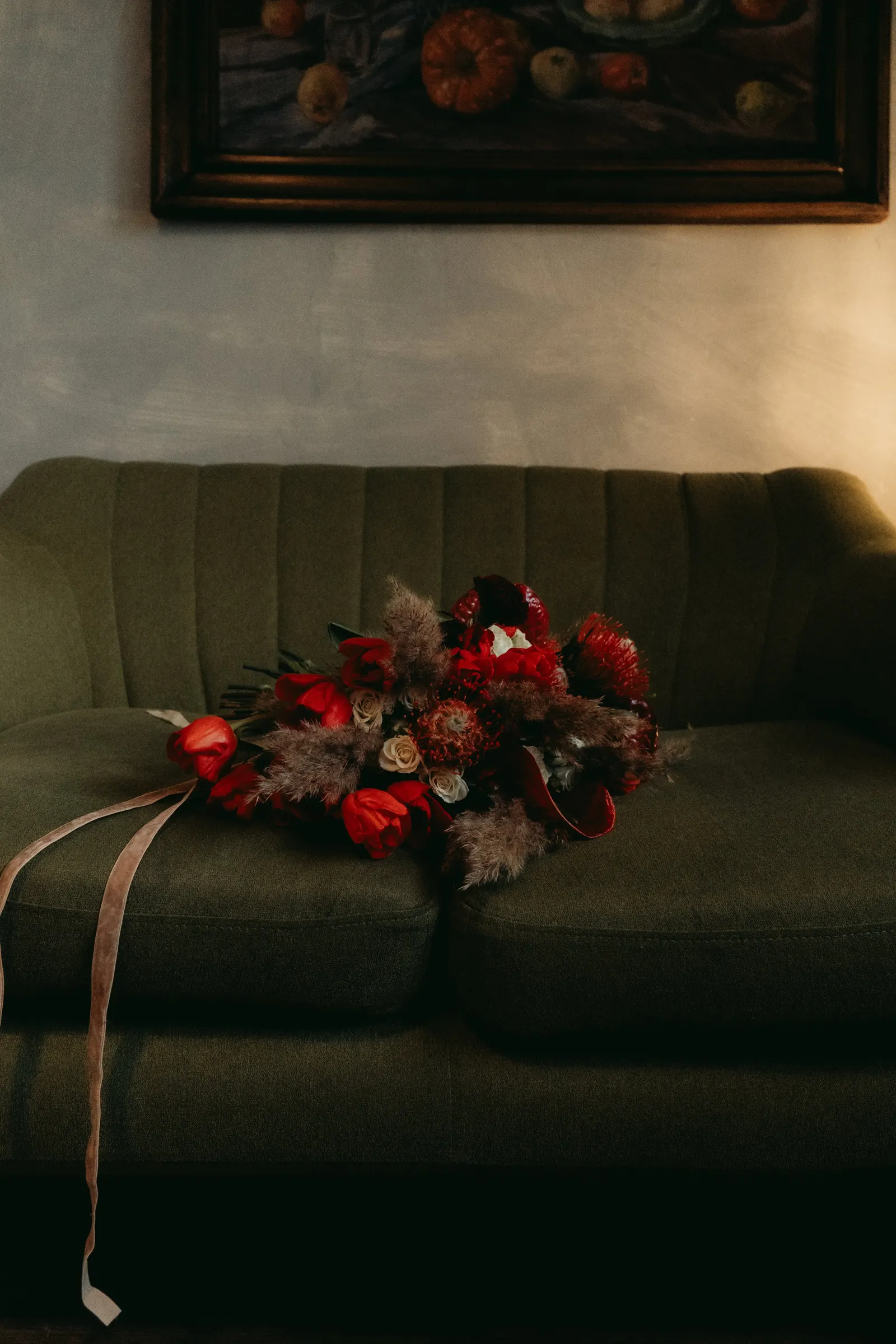 Winter editorial – bouquet of red flowers on a green sofa